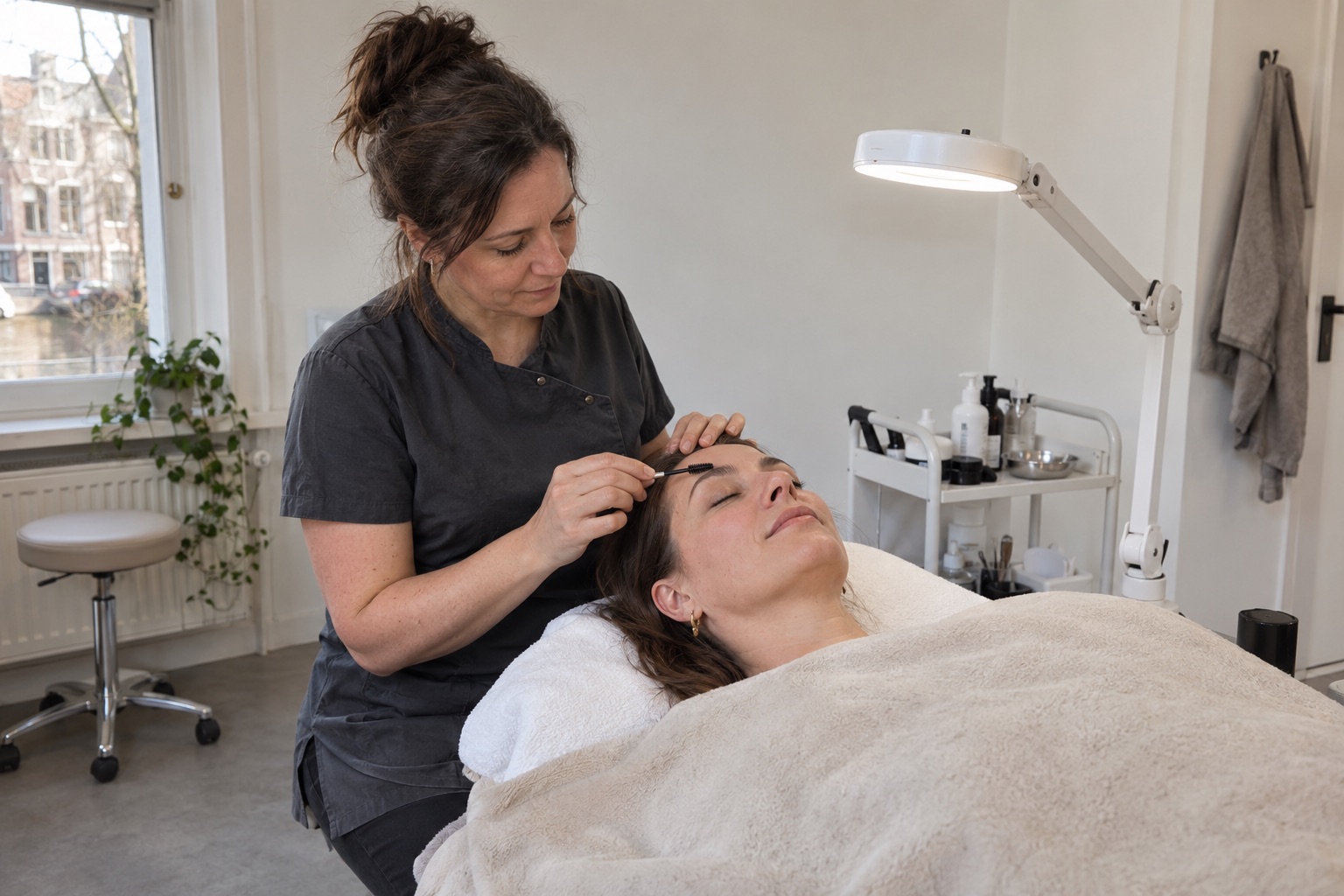 Een wenkbrauwstylist verzorgt de wenkbrauwen van een klant in een kleine studio.